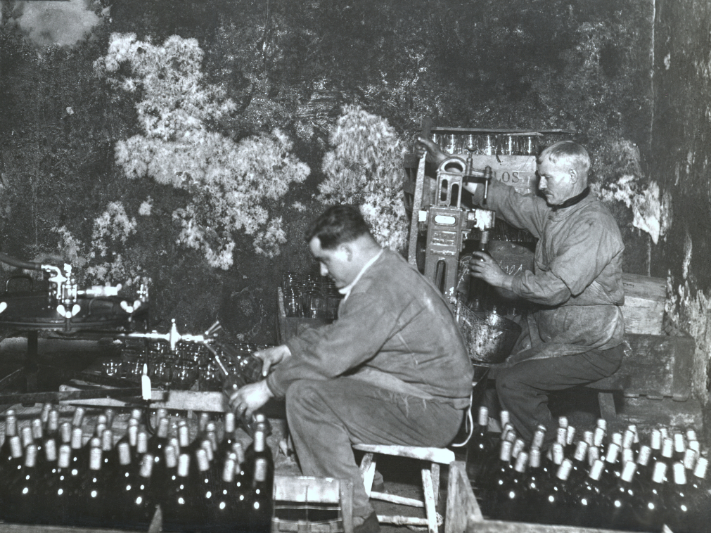Créer un vin – Maison Sichel Photographie d'archive d'ouvriers manipulant des bouteilles pour créer un vin